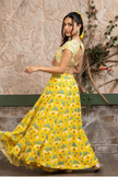 Woman wearing a yellow printed lehenga set with a hand-embroidered blouse and embroidered tulle dupatta in Senren's signature  bohemian print.