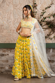 Woman wearing a yellow printed lehenga set with a hand-embroidered blouse and embroidered tulle dupatta in Senren's signature  bohemian print.