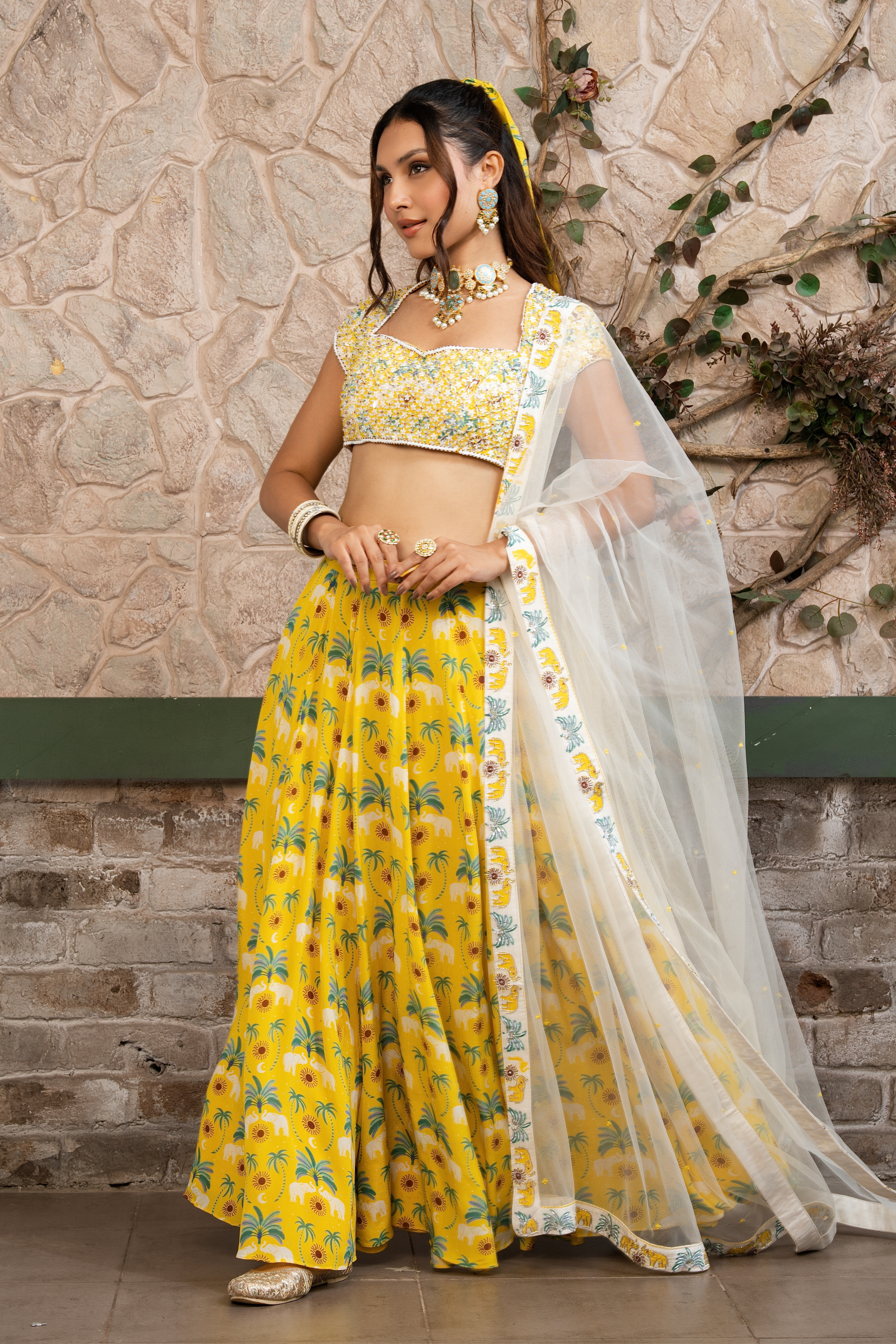 Woman wearing a yellow printed lehenga set with a hand-embroidered blouse and embroidered tulle dupatta in Senren's signature  bohemian print.