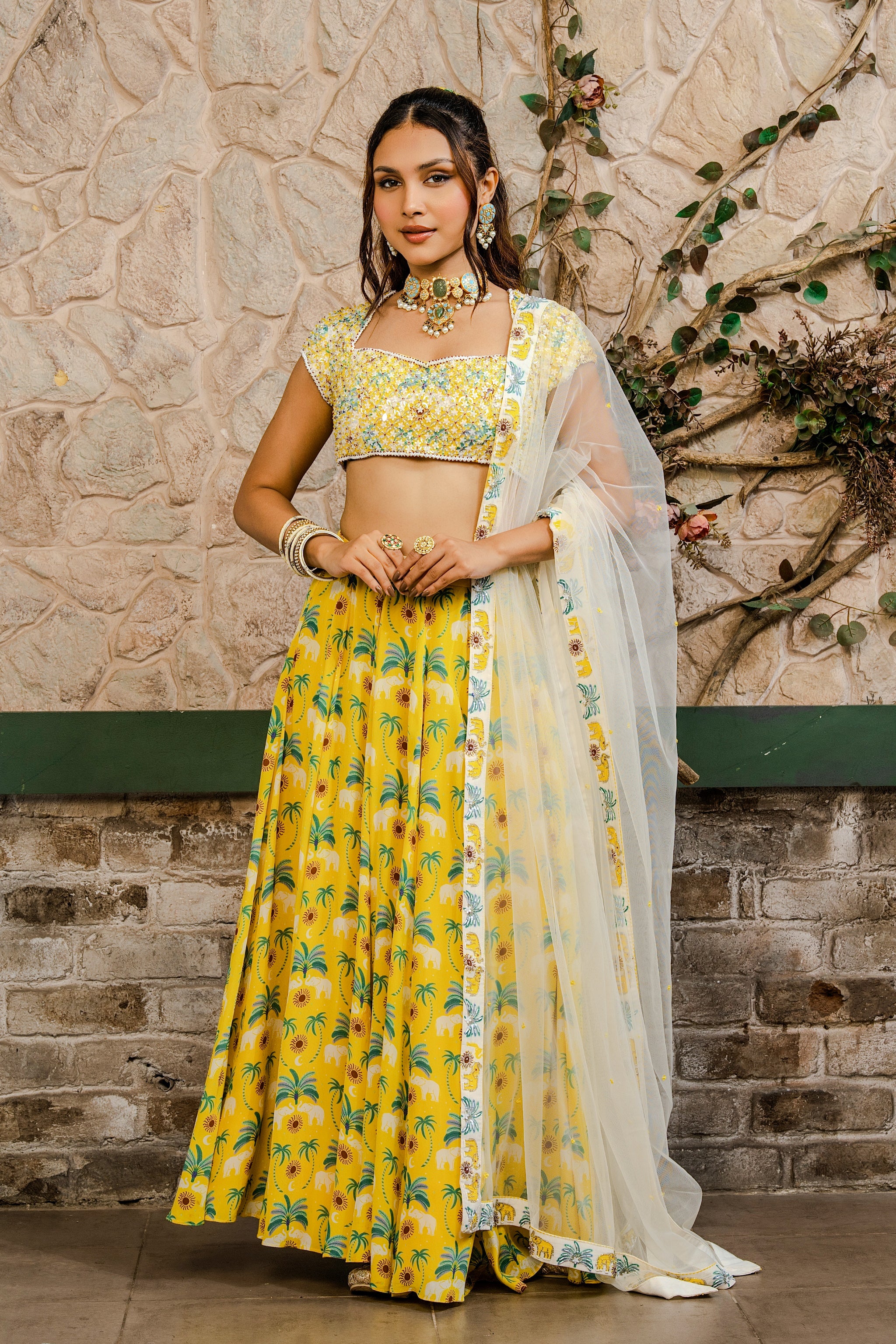 Woman wearing a yellow printed lehenga set with a hand-embroidered blouse and embroidered tulle dupatta in Senren's signature  bohemian print.