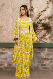 Woman wearing a yellow printed draped skirt set with a bustier blouse and embroidered cape in Senren's signature  bohemian print.