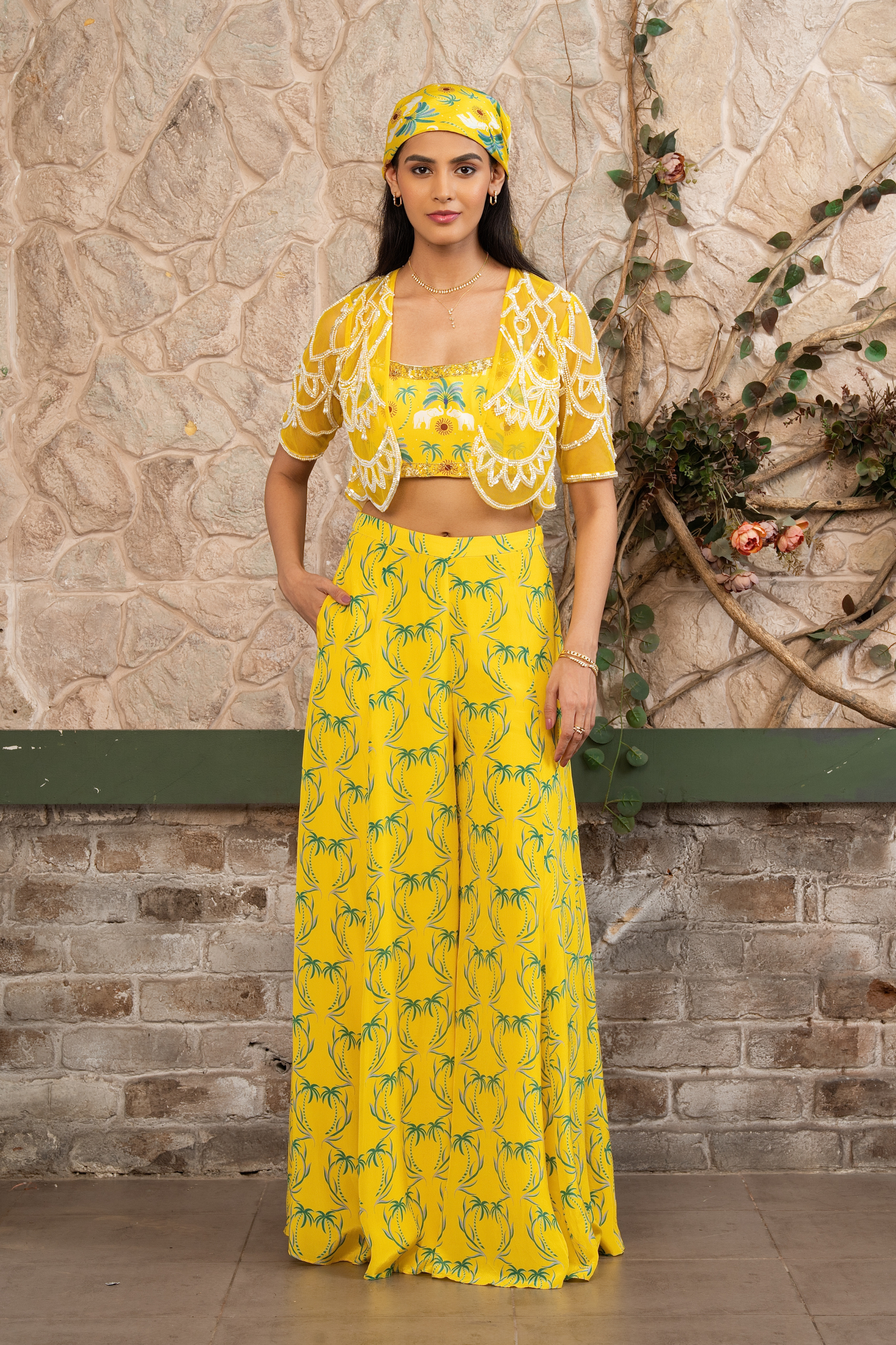 Woman wearing a yellow printed bustier with flowing sharara pants and a hand-embroidered cape in Senren's signature bohemian print.