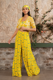 Woman wearing a yellow printed bustier with flowing sharara pants and a hand-embroidered cape in Senren's signature Nomad's Tale bohemian print.
