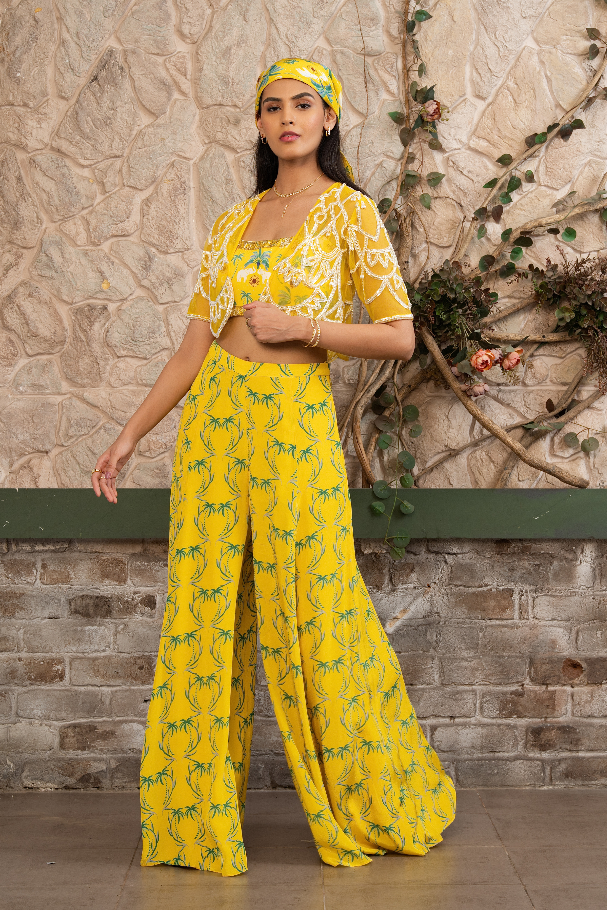 Woman wearing a yellow printed bustier with flowing sharara pants and a hand-embroidered cape in Senren's signature Nomad's Tale bohemian print.
