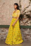 Woman wearing a yellow printed bustier with flowing sharara pants and a hand-embroidered cape in Senren's signature Nomad's Tale bohemian print.
