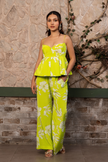 Woman wearing a lime green floral printed corset peplum co-ord set with wide-leg trousers