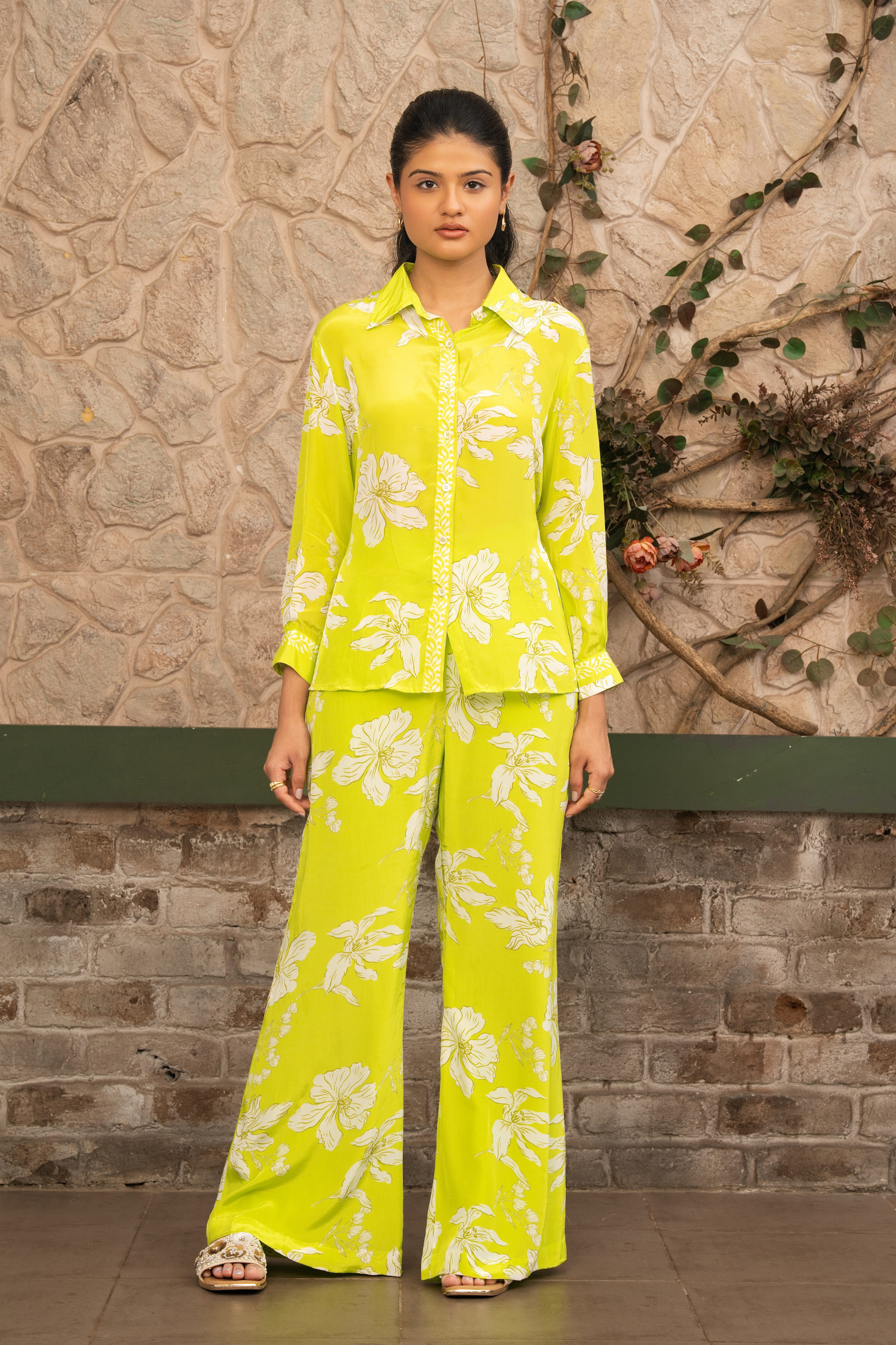 Woman wearing a lime green floral printed co-ord set with a button-down shirt and wide-leg trousers by Senren.