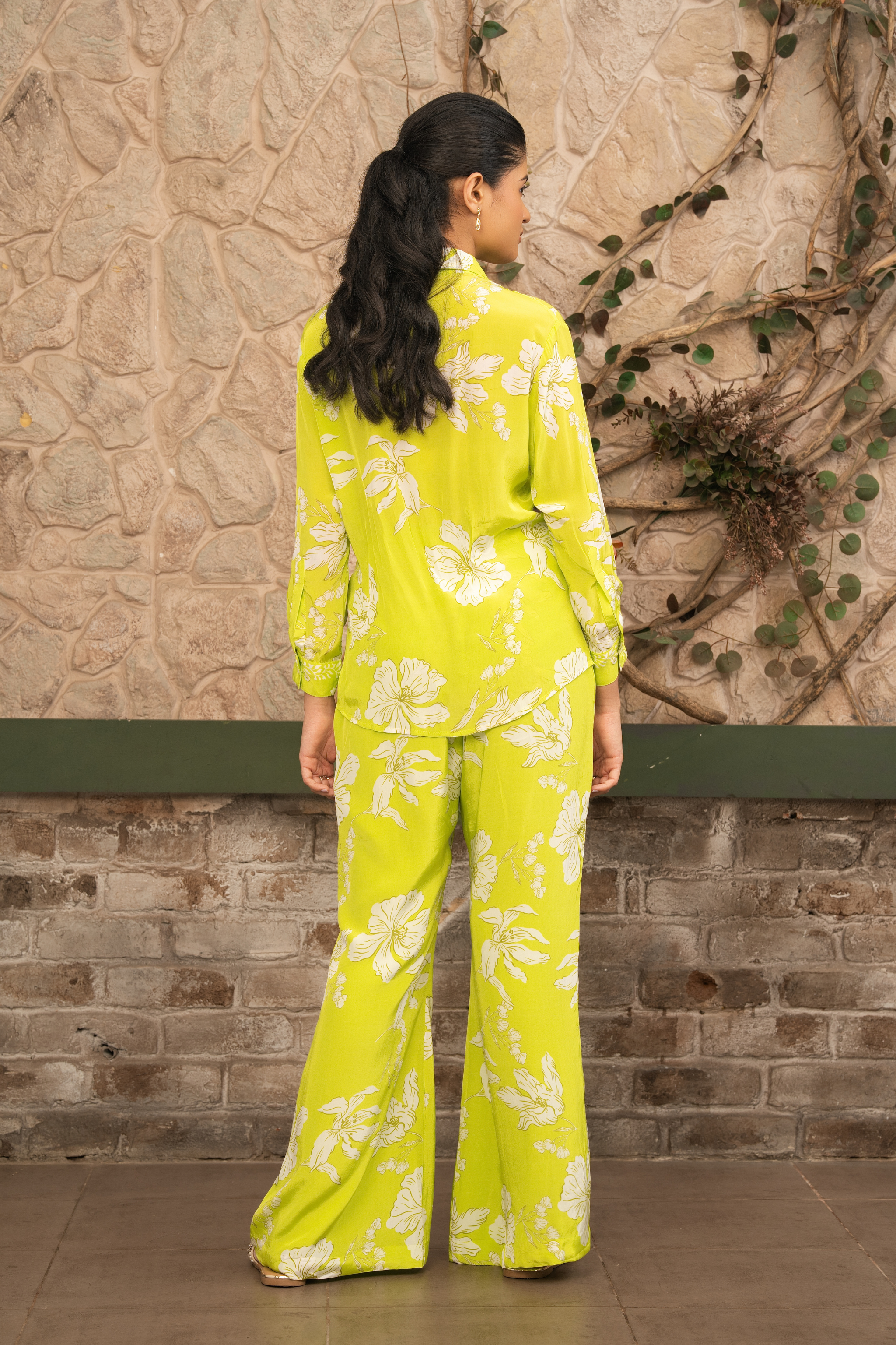 Woman wearing a lime green floral printed co-ord set with a button-down shirt and wide-leg trousers by Senren.