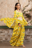 Woman wearing a yellow printed draped skirt set with a bustier blouse and embroidered cape in Senren's signature  bohemian print.