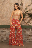 Woman wearing a hand-embroidered corset blouse with red boho printed wide-leg sharara pants.