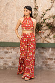 A woman modeling a red two-piece printed outfit consisting a red halter neck printed co-ord set with wide-leg sharara pants in Senren's signature bohemian print.