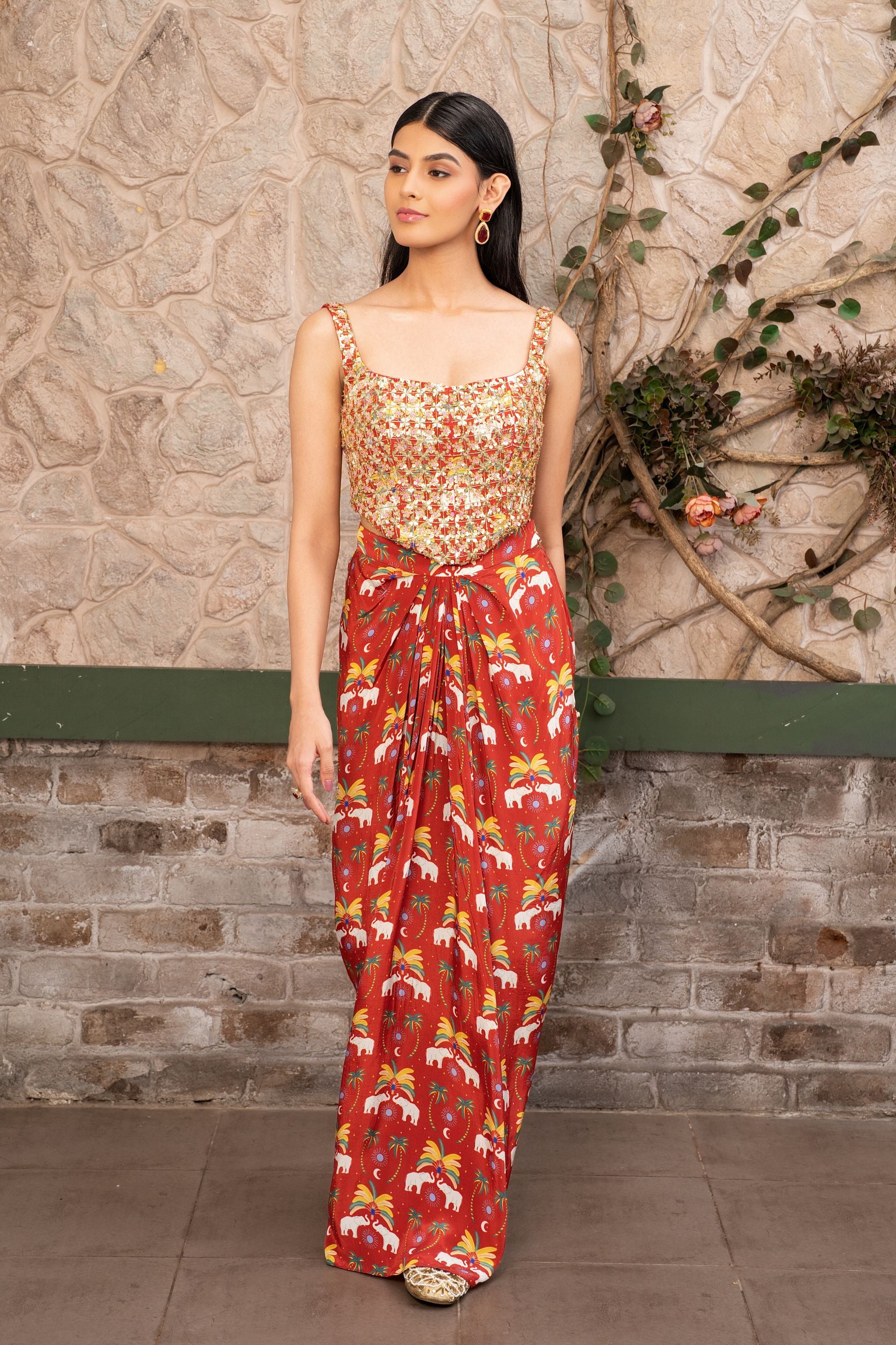 Woman wearing a hand-embroidered sequin bustier with a red printed draped skirt in Senren's signature bohemian print.