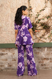 Woman wearing a purple floral printed embroidered ruffle peplum top with flared trousers in a luxury co-ord set by Senren.