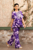 Woman wearing a purple floral printed embroidered ruffle peplum top with flared trousers in a luxury co-ord set by Senren.