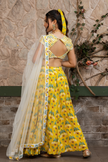 Woman wearing a yellow printed lehenga set with a hand-embroidered blouse and embroidered tulle dupatta in Senren's signature  bohemian print.